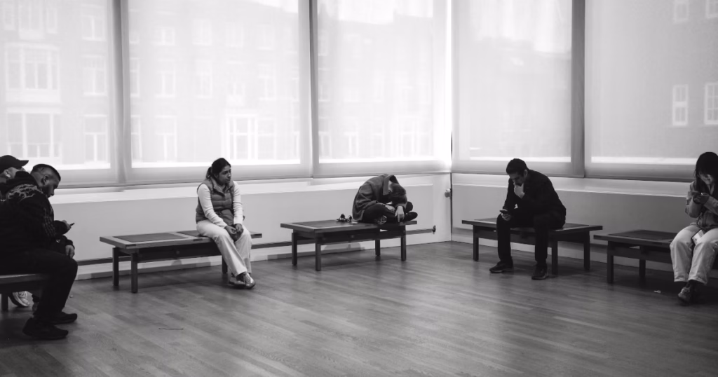 Students waiting on benches in a hall, symbolizing the real-world delays caused by financial aid bottlenecks.